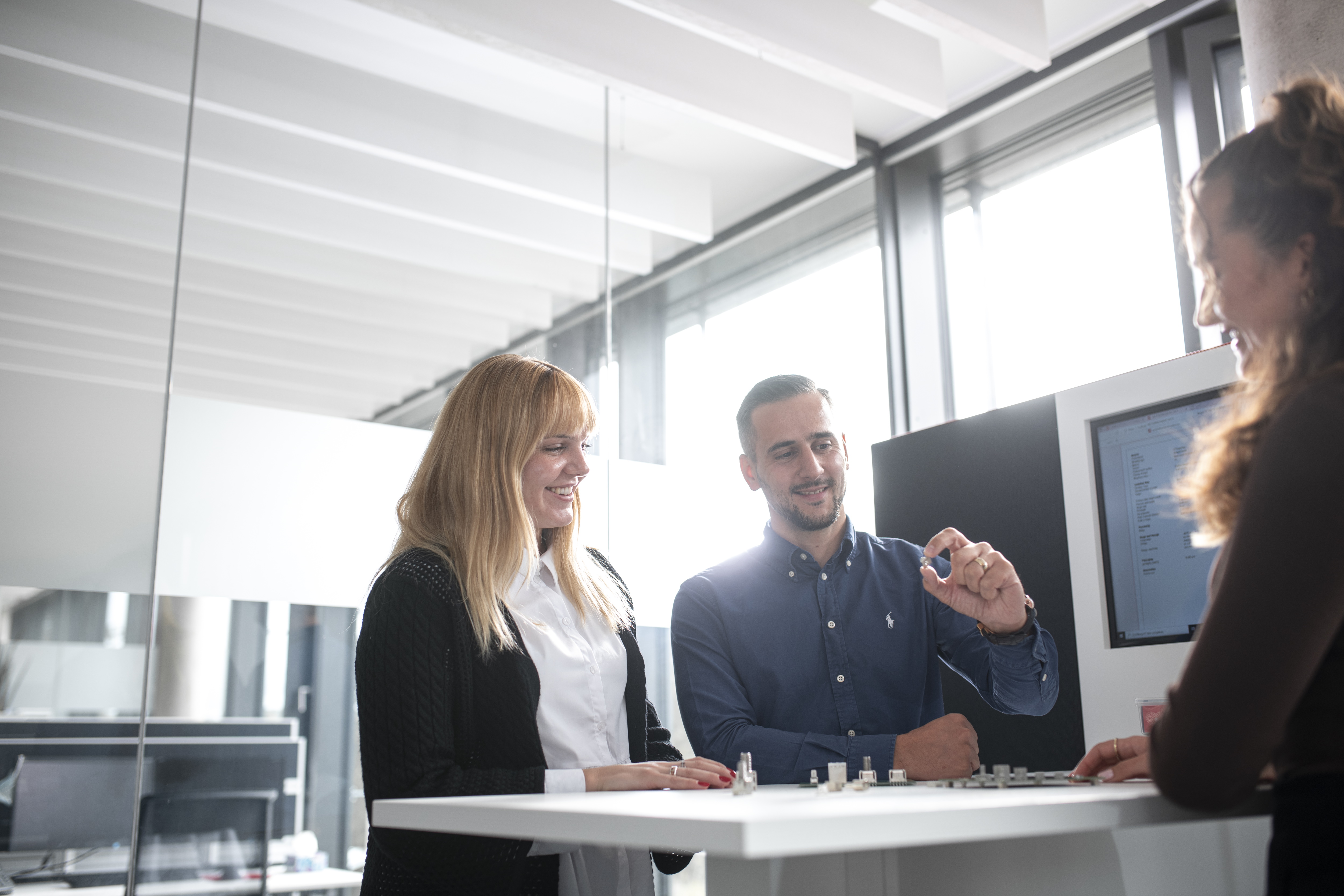 ICS Mitarbeiter Gruppenbild Mitarbeiter zeigt Mitarbeiterin ein Produkt