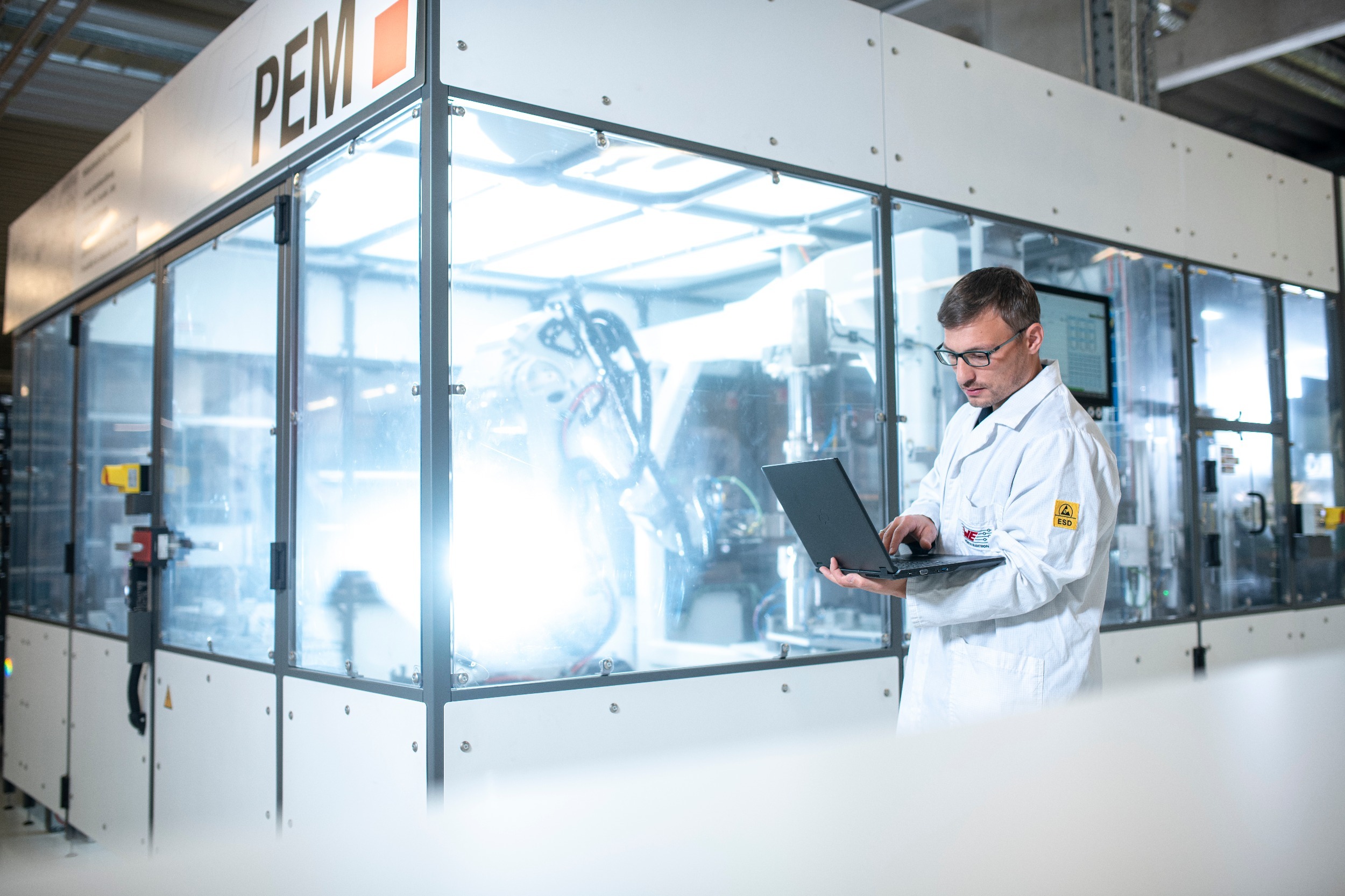 Competences processes and production worker in white jacket with laptop and PEM press-fit production machine