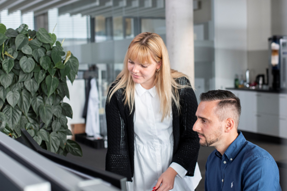 ICS Employees infront of Monitor Employee shows other employee something on monitor